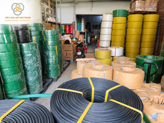 Hình ảnh thực tế kho dây đai PET với nhiều cuộn dây màu xanh, vàng, trắng và đen, phục vụ các nhu cầu đóng kiện và cố định hàng hóa.